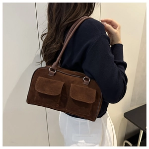 Detail view of a vintage dark brown suede shoulder bag with dual front flap pockets
