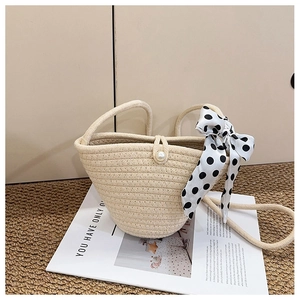 Détail du sac seau tressé beige avec fermoir perle et poignée en foulard de soie
