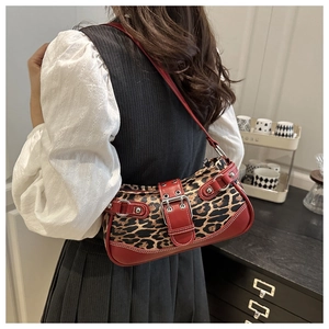 Detail of leopard print shoulder bag featuring red leather trim and silver metal eyelets