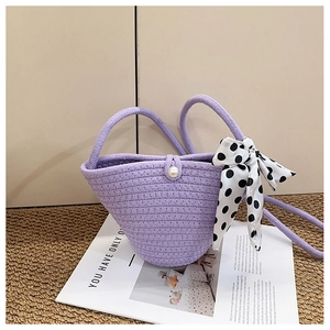Détail du sac seau violet tressé avec bouton perle et nœud en ruban à pois élégant