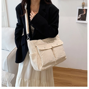 Detail of cream corduroy tote bag featuring dual front flap pockets and adjustable wide strap