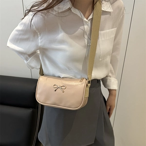 Minimalist beige crossbody bag with gold bow and wide strap for casual summer wear