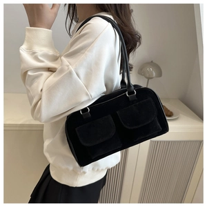 Detailed view of a black suede handbag with double square pockets on a fashion model