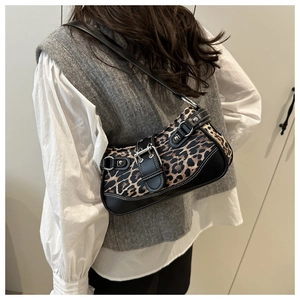 Chic leopard print underarm bag with black leather trim and silver buckles worn on shoulder