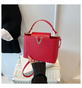Detailed view of red woven handbag with metallic V-logo and slim adjustable shoulder strap