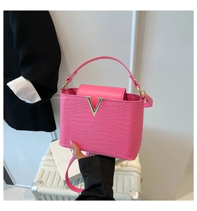 Detailed close-up of pink woven texture handbag with V-shaped silver metal buckle and handle