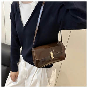 Close-up of brown patent leather crossbody bag with elegant gold metal twist lock buckle