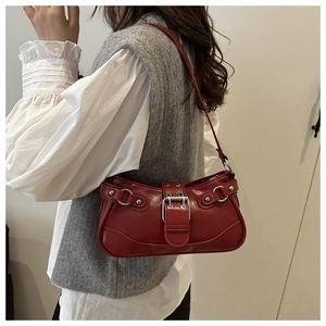Detail of red leather shoulder bag featuring silver buckle and vintage Y2K rivets