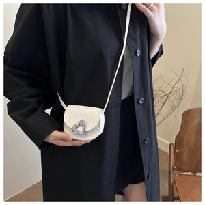 Close-up of a white lychee leather mini crossbody bag with a silver heart-shaped clasp