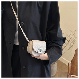 Detail of beige litchi leather mini bag with silver heart-shaped metal buckle and strap