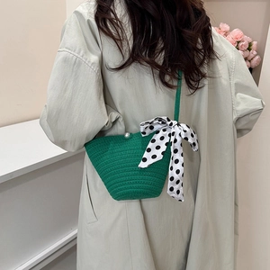 Sac seau tissé vert avec boucle en perle et nœud à pois sur modèle en trench
