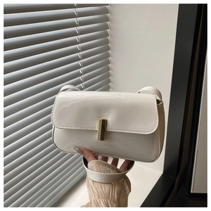 Detail of white patent leather handbag featuring a rectangular gold metal buckle