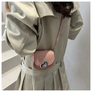 Close-up of pink mini heart saddle bag featuring silver metal twist lock on lychee grain leather