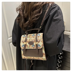 Detail of retro geometric woven crossbody bag with leather trim and metal logo plate