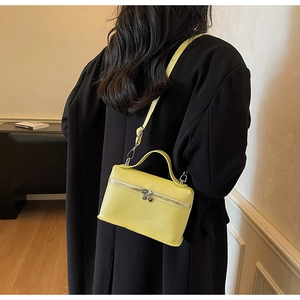 Rear view of a model wearing a lemon yellow litchi leather crossbody box bag with heart zipper
