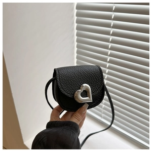 Détail du sac en cuir noir à texture litchi avec fermoir métallique en forme de cœur argenté