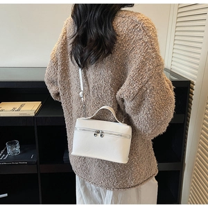 Close-up of white pebble leather crossbody bag with silver heart-shaped zippers