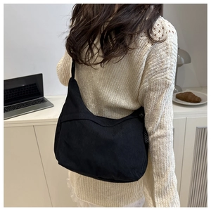 Gros plan du sac bandoulière en velours côtelé noir montrant la texture et la capacité
