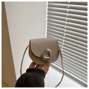 Détail de la boucle en métal argenté en forme de cœur sur un sac en cuir beige