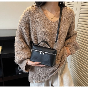 Detail of black pebbled leather crossbody bag with silver heart-shaped zipper puller