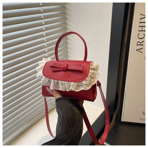Detail of red faux leather mini bag featuring white lace trim and bow decoration