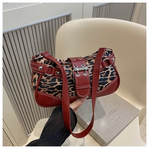 Detail of leopard print underarm bag with red leather trim and silver metal eyelet straps