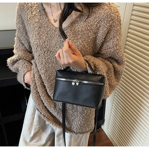Close-up of black litchi grain crossbody bag with a heart-shaped silver zipper puller