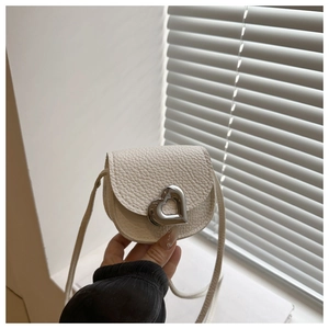 Détail d'un mini sac blanc en cuir texturé litchi avec boucle en métal en forme de cœur