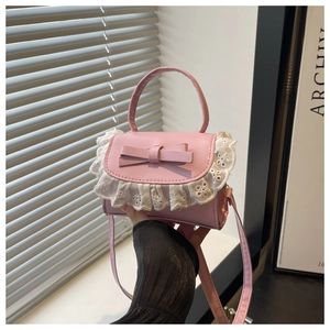 Detailed shot of pink PU crossbody bag with decorative bow and white lace embroidery
