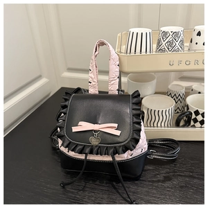 Detail eines süßen Lolita-Rucksacks mit Spitzenborte, rosa Schleifen und Herzanhänger