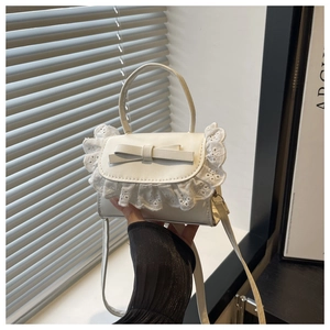 Close-up of white mini crossbody bag featuring lace trim and a delicate bow detail