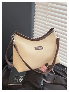 Detail of canvas crossbody bag with brown leather trim and adjustable shoulder strap