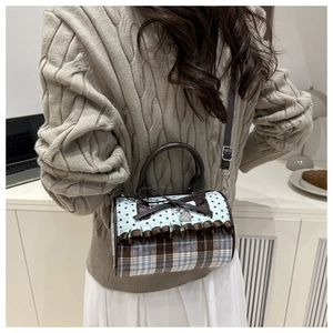 Vue détaillée du sac polochon à carreaux avec nœud porté en bandoulière par un mannequin