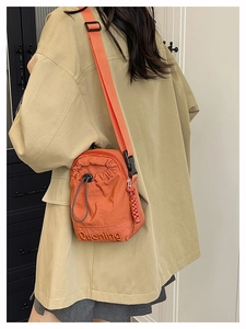 Close-up of orange nylon bucket bag with Duoning embroidery and woven zipper detail