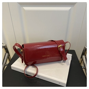 Detail of red patent leather square bag with gold logo and adjustable shoulder strap