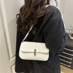 Glossy white patent leather shoulder bag with gold clasp shown on a model