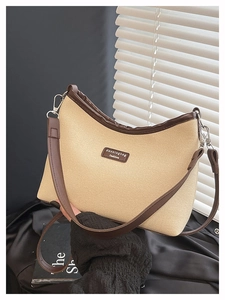 Detail of beige woven dumpling bag with brown leather trim and silver metal hooks
