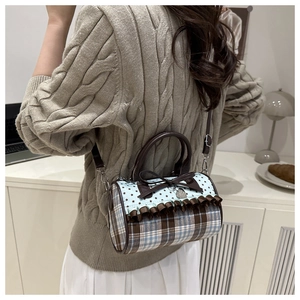 Détail d'un sac Boston à carreaux vintage avec nœuds porté à l'épaule pour femme