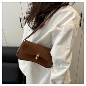 Detail of a brown leather shoulder bag with an oval gold metal buckle and smooth finish