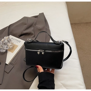 Close-up of black litchi grain leather square bag with silver heart-shaped zipper pulls