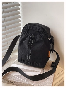 Close-up of black nylon bucket bag with orange fashion tag on vintage books background