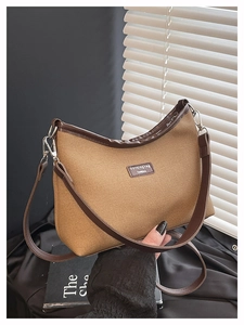 Detail of camel canvas dumpling bag featuring dark brown leather trim and silver metal zipper
