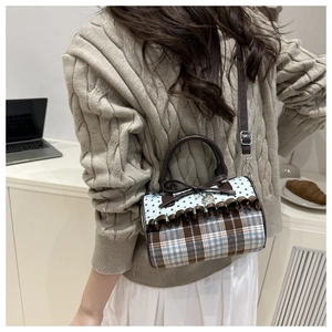 Détail d'un sac oreiller à carreaux avec nœud papillon, pendentif cœur et bandoulière