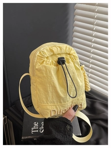Detail of yellow nylon drawstring bag featuring golden logo embroidery and adjustable strap