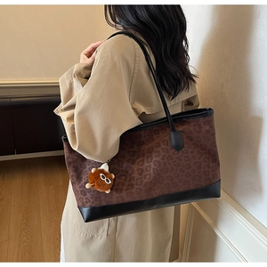 Detail showing high-quality leopard print fabric and black leather trim on a tote bag