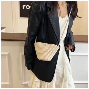Detail of hand-woven bucket bag featuring a white pearl clasp and textured fiber finish