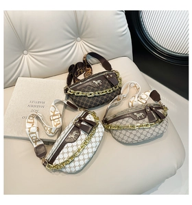 Three printed saddle chest bags with thick gold chains and wide patterned straps on soft background