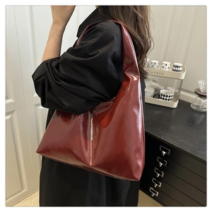 Close-up of a burgundy patent leather hobo bag with a glossy finish and minimalist design