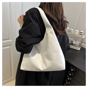 Minimalist white leather hobo bag with wide shoulder strap shown on model's shoulder