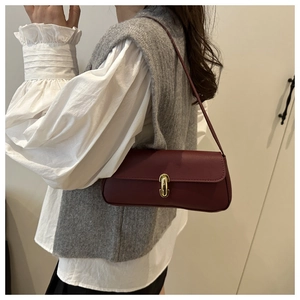 Detail of burgundy leather shoulder bag with vintage gold clasp on model